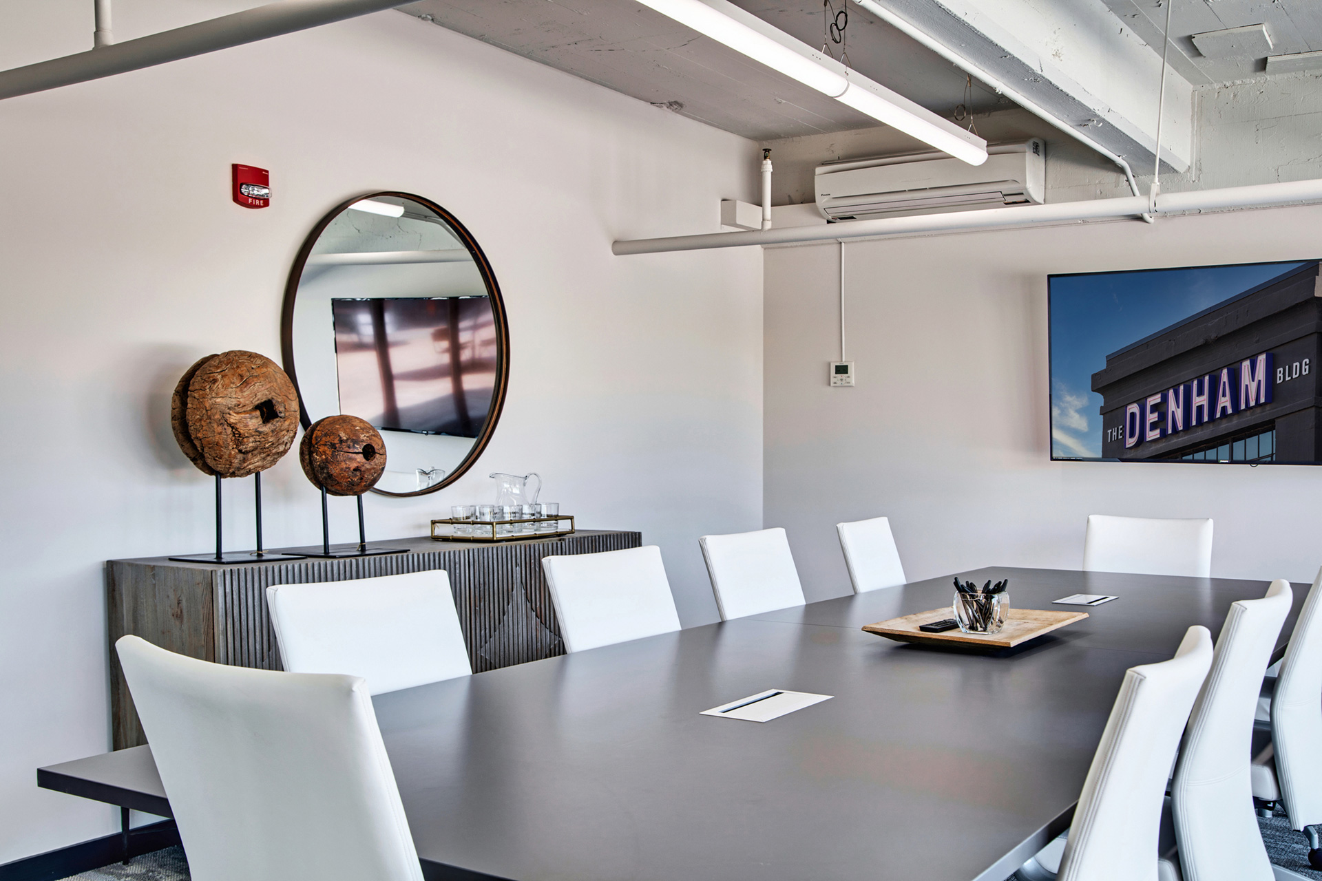 Conference room with large table and multiple white office chairs for working professionals at The Denham Building loft apartments for rent
