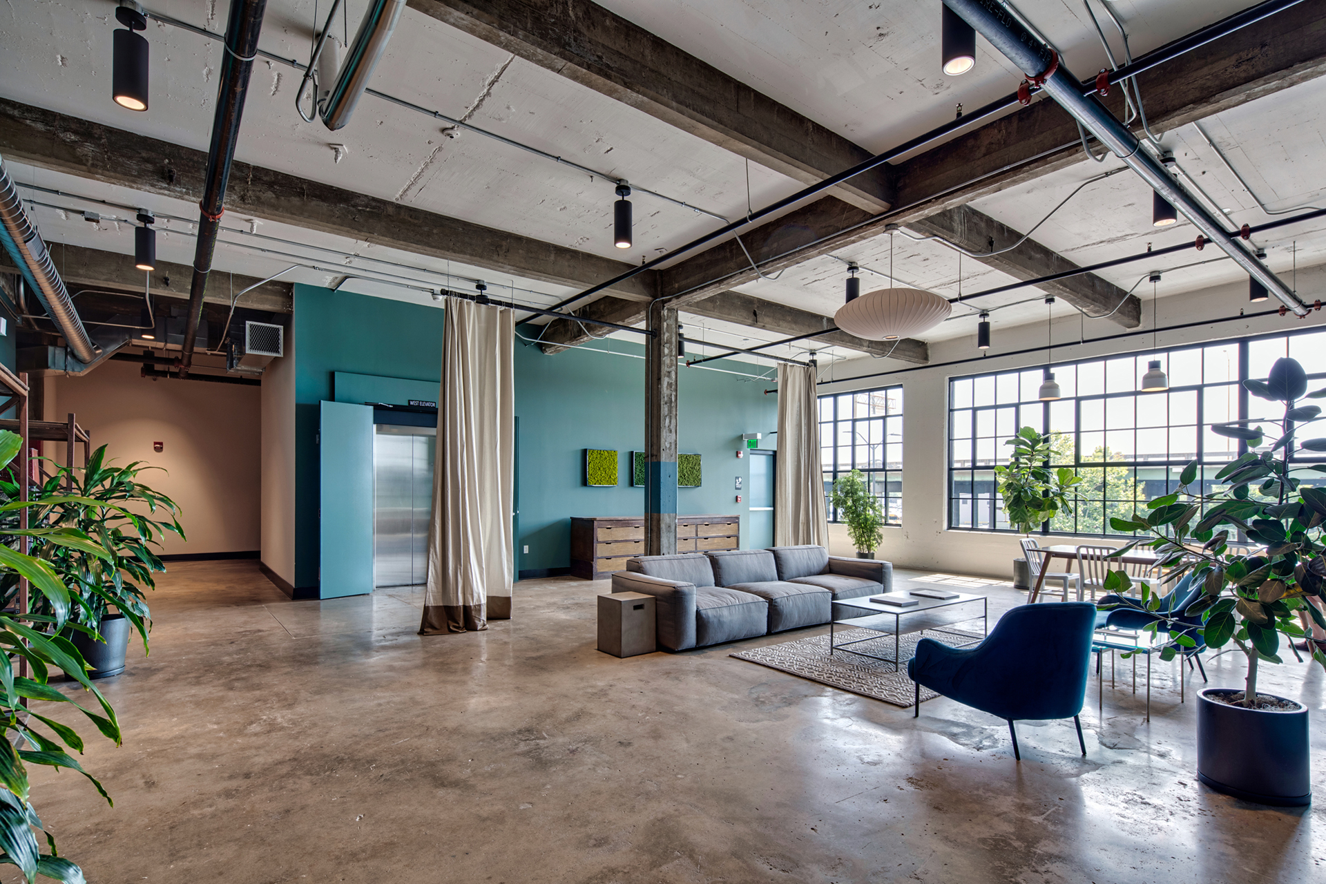 Large lobby area with ample seating, indoor plants, and windows for natural light at The Denham Building loft apartments for rent in South Birmingham, AL