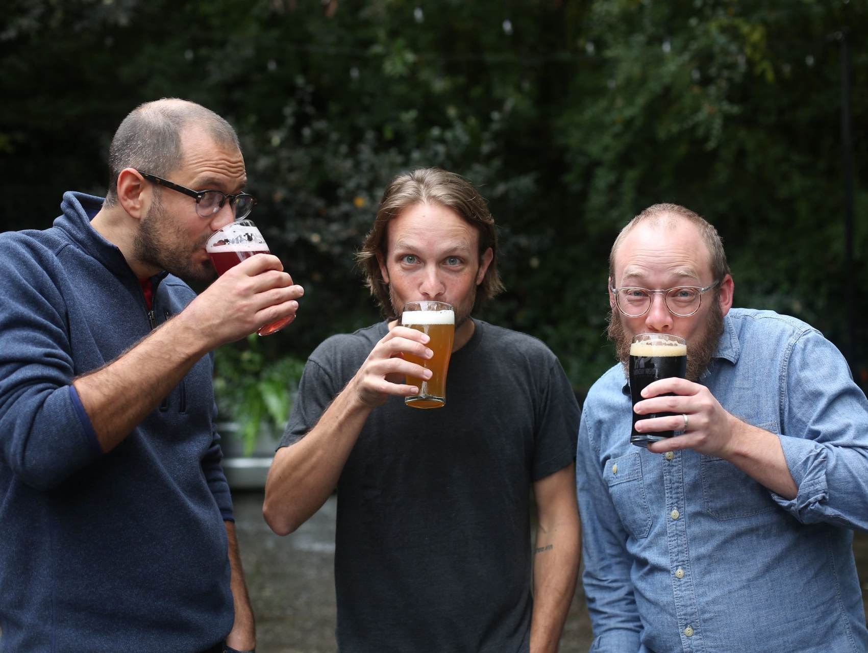 Three men drinking beer at Monday Night Brewing brew pub at The Denham Building loft apartments for rent